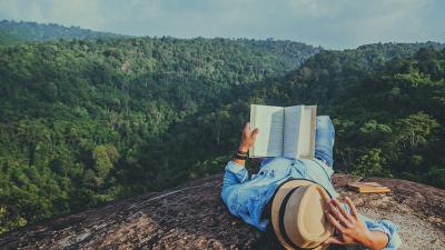man reading one of the best science books - on a mountaintop as nature intended
