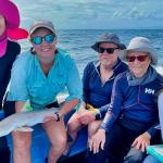 Five people posing on a boat in Belize after tagging a shark for research purposes.