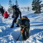 Earthwatch volunteers digging in the snow to conduct snowpack research.