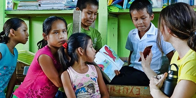 A woman showing a group of children her photo in Iquitos, Peru.