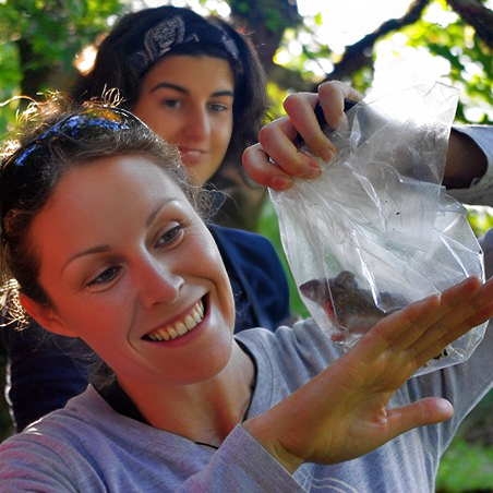 Two women examining a rodent they caught for research purposes.