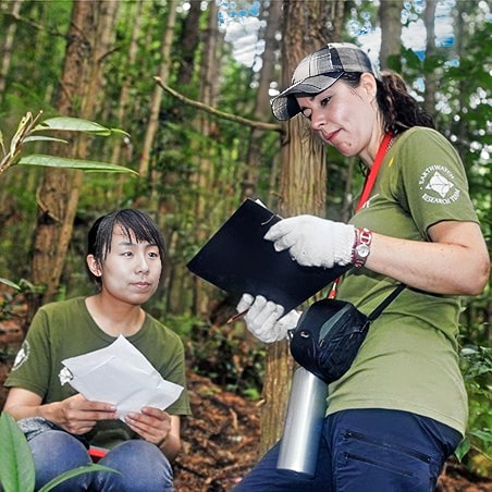 Two women reviewing recorded data in the forest.