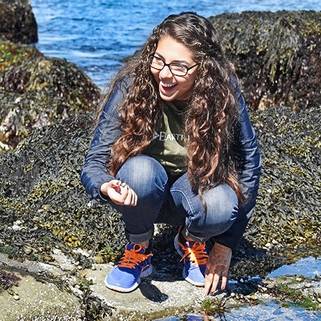 A teen girl with a shell in her hand enjoying her expedition at Acadia National Park.